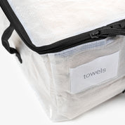 Clear travel bag with black zipper and 'towels' label on a white background