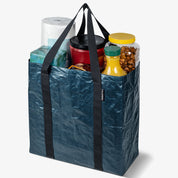 Blue reusable shopping bag filled with groceries on a white background