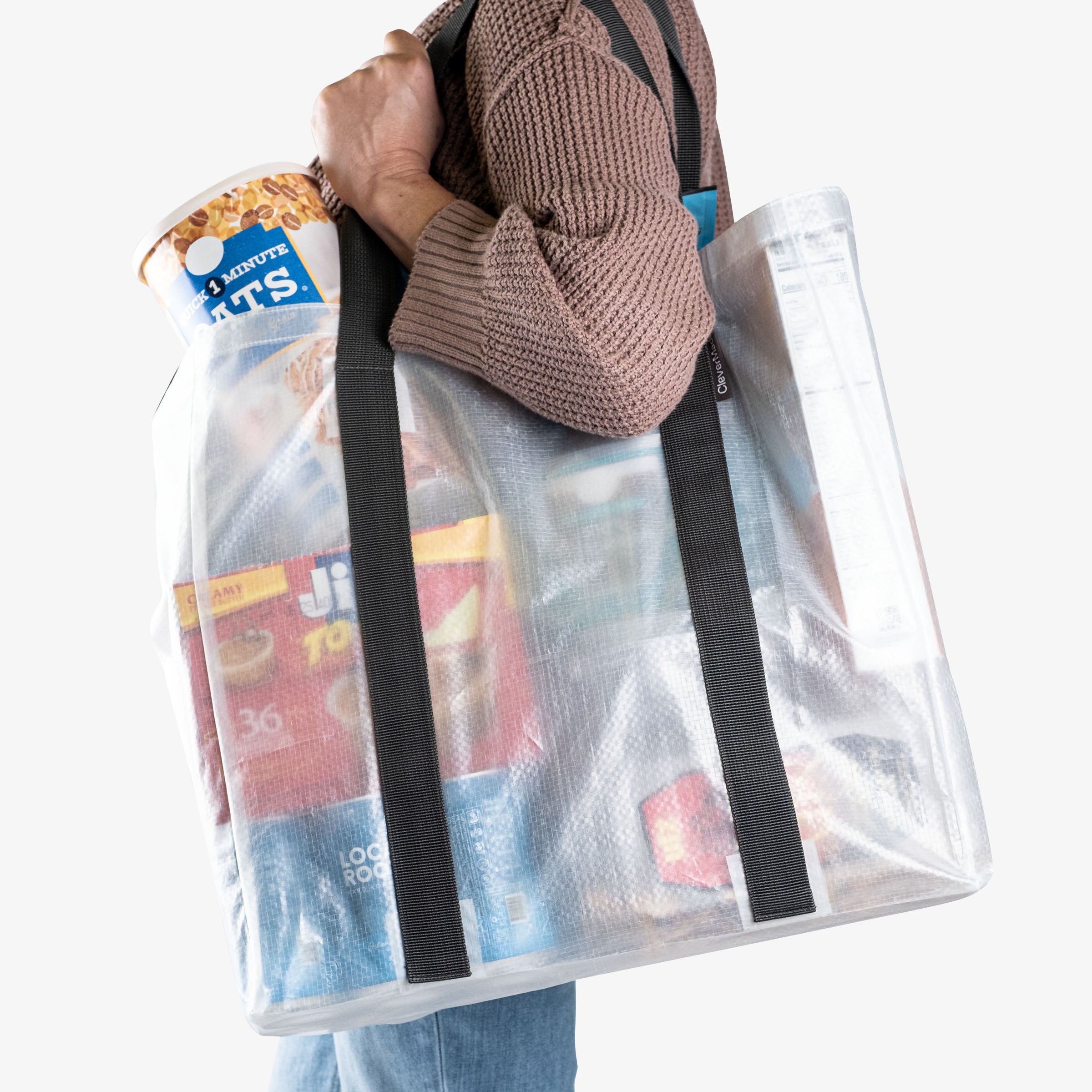 Person carrying clear reusable shopping bag with snacks on her shoulder
