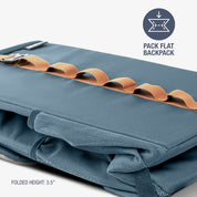 Folded blue backpack cooler with brown accents on a white background
