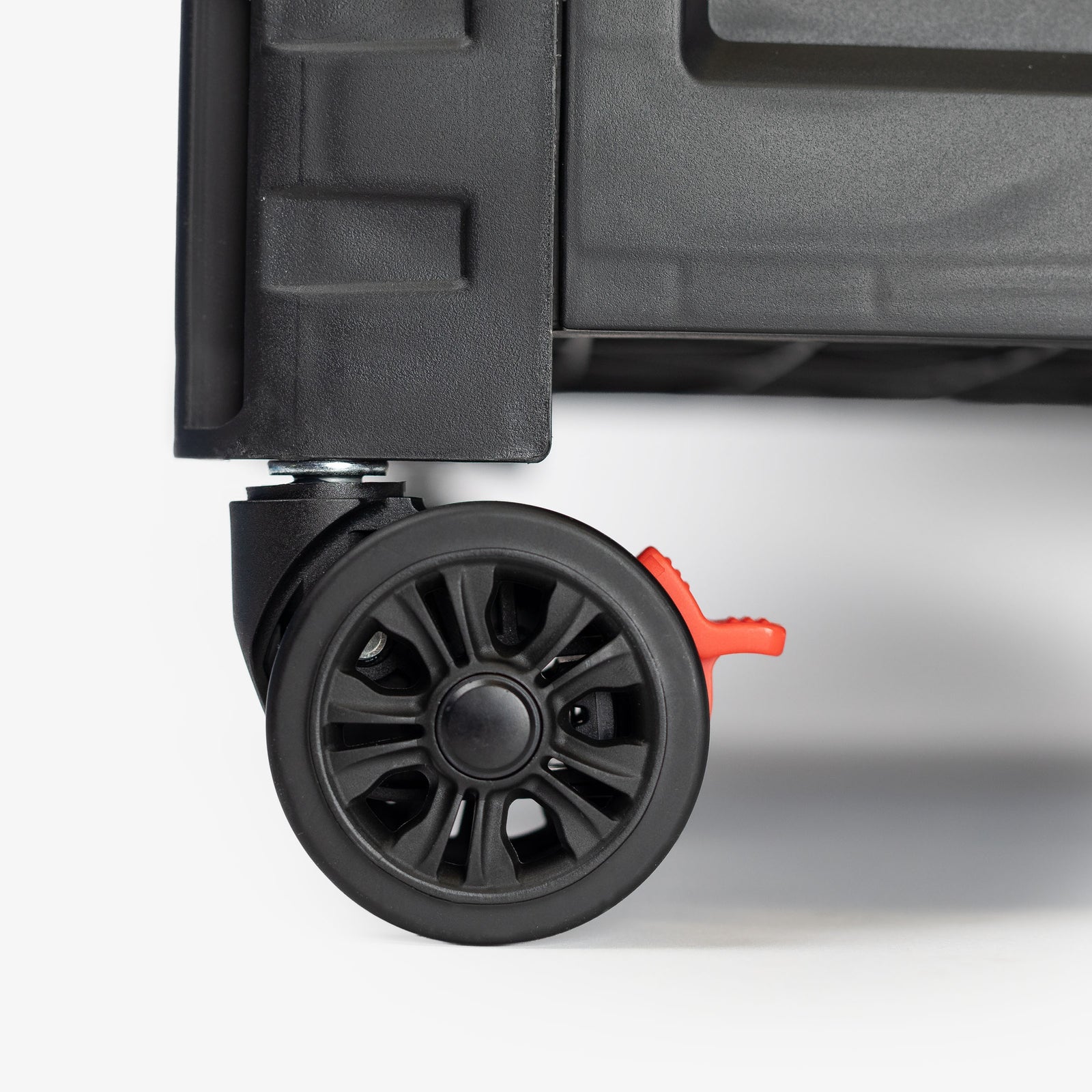 Close-up of a suitcase wheel with a red brake lever on a white background